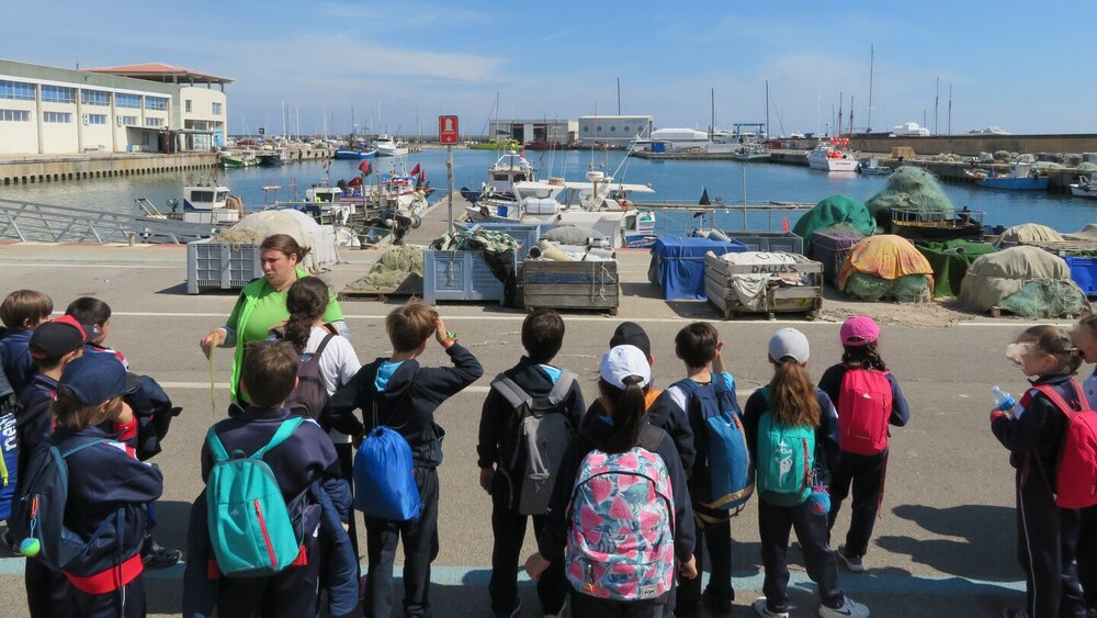 nens al port amb barques de pesca